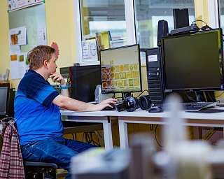 Ein Mann arbeitet an einem Computer in einem Büro mit mehreren Bildschirmen.