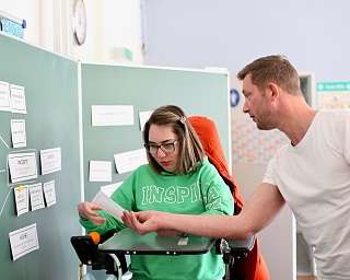 Eine Person hilft einer anderen beim Lernen in einem Klassenzimmer.