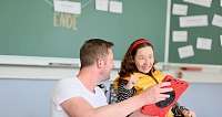 Eine Frau und ein Mann interagieren in einem Klassenzimmer.