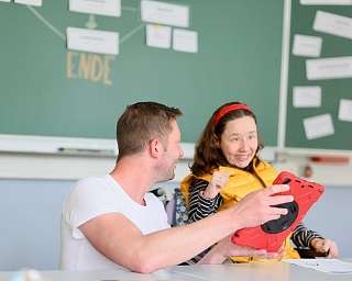 Lehrer und Schülerin interagieren in einem Klassenzimmer.