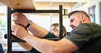 Zwei Männer arbeiten zusammen an einem Möbelstück.
