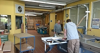 Zwei Personen arbeiten in einer Holzwerkstatt mit Maschinen.
