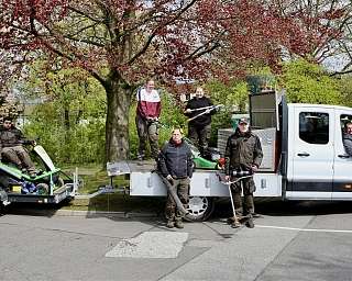 Ein Team von Gärtnern steht neben einem Fahrzeug und Equipment.