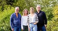 Vier Personen stehen in einem grünen Garten zusammen.