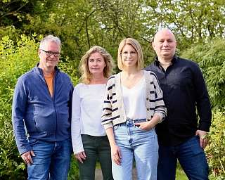 Eine Gruppe von vier Personen steht in einem Garten.