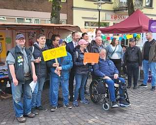 Menschen stehen zusammen und halten Schilder auf einer Veranstaltung.