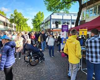 Belebte Straße mit Ständen und Besuchern bei einer Veranstaltung.