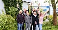 Sechs Personen posieren fröhlich im Garten.