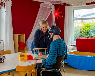 Eine Therapeutin interagiert mit einem Kind in einem Therapieraum.