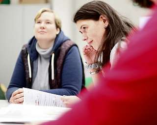 Zwei Frauen hören aufmerksam in einer Gruppensitzung zu.