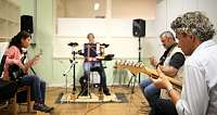 Vier Musiker spielen gemeinsam in einem Proberaum.
