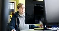 Eine Person arbeitet konzentriert an einem Computer in einem Büro.